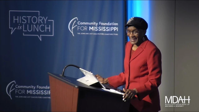 Dr. Alferdteen Brown Harrison speaking at a podium during a History Is Lunch program